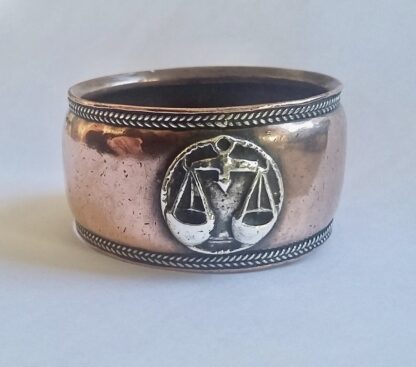 Artificers Guild (attributed), an Arts and Crafts copper and silver Libra zodiac symbol napkin ring, circa 1925 SOLD